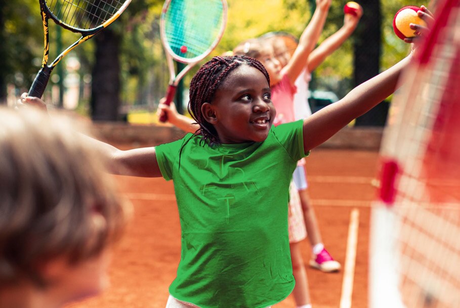 A young girl practices her tennis serve on a court.